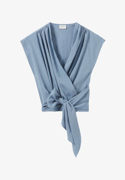 Blouse sans manches bleu clair avec des rayures verticales, devant croisé et un nœud noué à la taille.