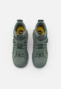 Tumedadid sneakers muted rohelisest seemisnahast, mustade paeltega, kollase voodriga ja tekstuuriga kummitaldadega, mille ülaosas on silmatorkav bränding.