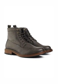 Brown leather ankle boots with a rounded toe, contrasting light brown sole, and lace-up design featuring gold-tone eyelets and pull tabs.