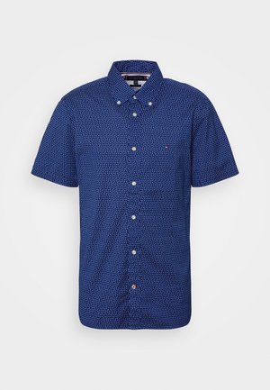 Blaues Hemd mit kurzen Ärmeln, kleinem weißem geometrischem Muster und Knopfleiste am Kragen auf weißem Hintergrund.