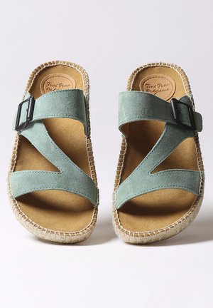 Žalie nubuko sandalai su kryžminėmis juostelėmis ir juodu sagtimi; jūrinis ir gumos padas su siūlų detalizavimu; lengvas ir ergonomiškas dizainas.