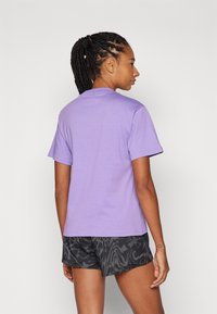 Μωβ βαμβακερό μπλουζάκι με κοντά μανίκια, κλασική λαιμόκοψη, συνδυασμένο με μαύρες βερμούδες με σχέδιο. Λείος υφάσματος, κλασική εφαρμογή, πίσω όψη.