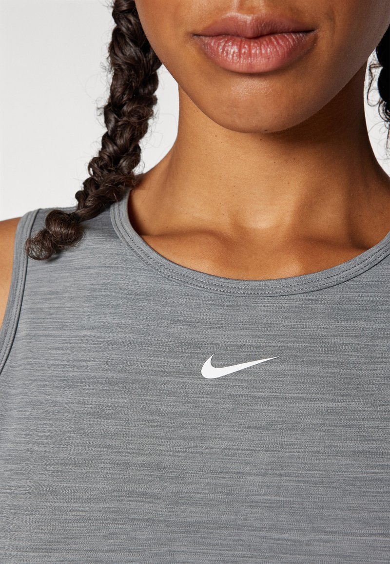 Débardeur de sport grise avec un col rond, fabriqué en tissu texturé, avec un petit logo Nike blanc centré sur la poitrine.