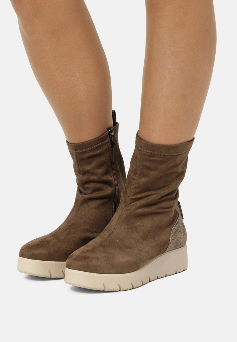 Stivaletti alla caviglia in suede marrone con dettagli laterali testurizzati e suola in gomma color crema, dotati di cerniera e design arricciato.