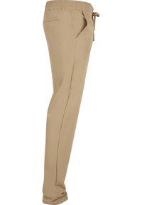 Pantalon beige slim fit avec taille élastique et cordon, avec poches latérales et arrière.