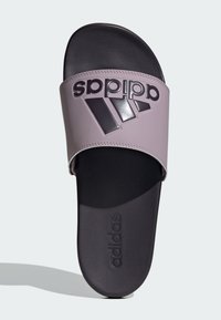 Adidas šľapky s fialovým remienkom, s čiernym logom a textúrovanou čiernou podrážkou. Hladký syntetický zvršok s dizajnom na jednoduché natiahnutie.