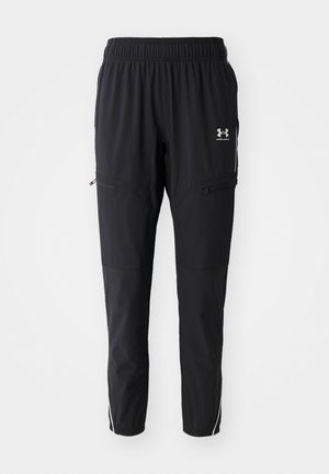 Black athletic pants with an elastic waistband, side pockets with zippers, and contrasting white stripes along the sides. Lightweight material.