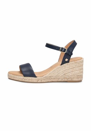 Sandalia de cuña con tiras de cuero azul marino, hebilla ajustable en el tobillo y plataforma de yute trenzado.