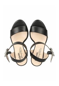 Sandales à talons hauts en cuir noir avec deux larges brides, dont une ornée d'un bijou décoratif sur la bride de la cheville. Doublure intérieure lisse.