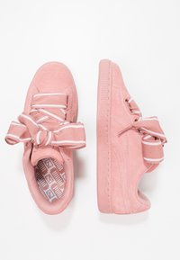 Růžové semišové sneakers s texturovaným povrchem, se zvýrazněnými mašlemi na tkaničkách a vzorovanou stélkou. Gumová podrážka s mírným vyvýšením.