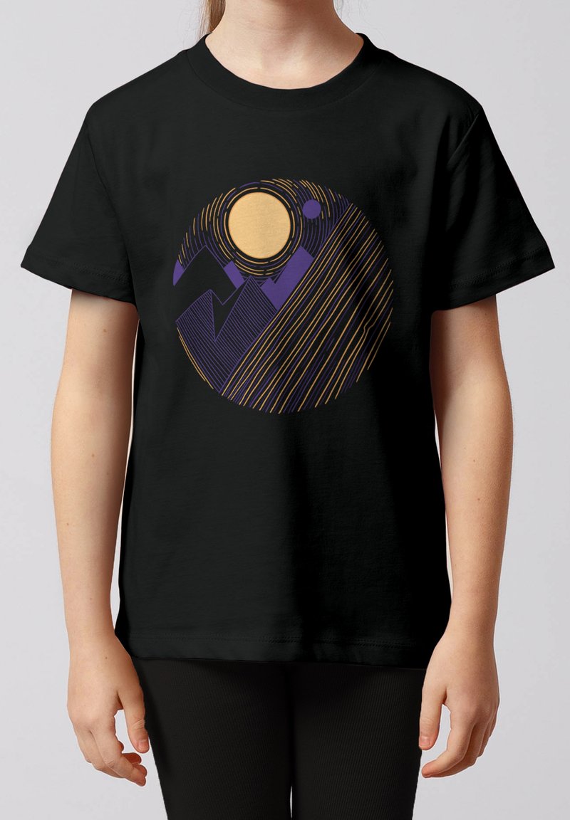Enfant portant un T-shirt noir avec un dessin abstrait circulaire représentant un soleil orange, des montagnes violettes et des lignes diagonales orange.
