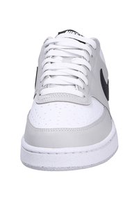White and grey sneaker with leather and synthetic materials. Features round toe, white laces, black accents, and textured sole.
