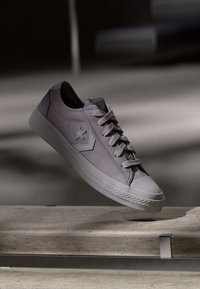 Low-top sneaker in light lavender suede with a rubber sole. Features a star logo, white laces, and a textured toe cap. Floating display.