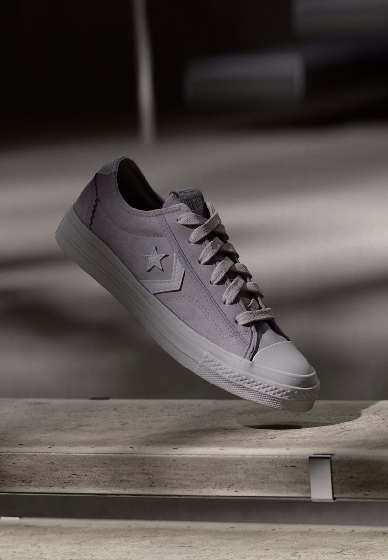Low-top sneaker in light lavender suede with a rubber sole. Features a star logo, white laces, and a textured toe cap. Floating display.