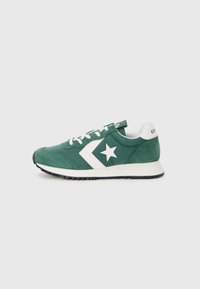 Zapatillas de gamuza verde con diseño de estrella blanca y chevron, cordones blancos y suela de goma negra. Estilo atlético clásico, silueta de corte bajo.