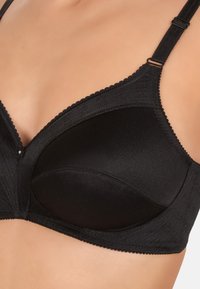 Reggiseno imbottito nero con spalline regolabili, caratterizzato da un bordo ondulato e una sottile trama sul tessuto, progettato per supporto e comfort.