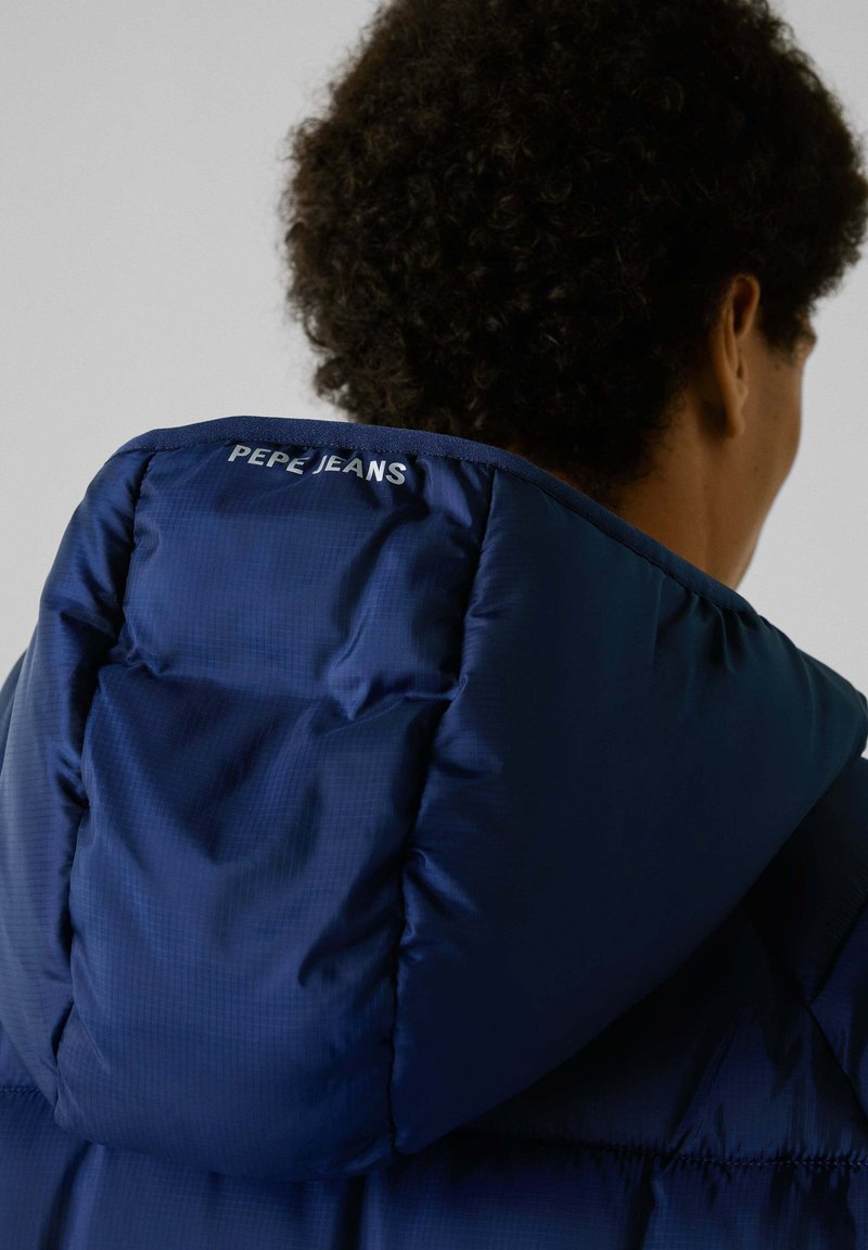 Marine pufferjack met capuchon, voorzien van een gestikte textuur en logodetail op de achterkant. Glad materiaal met een glanzende afwerking.