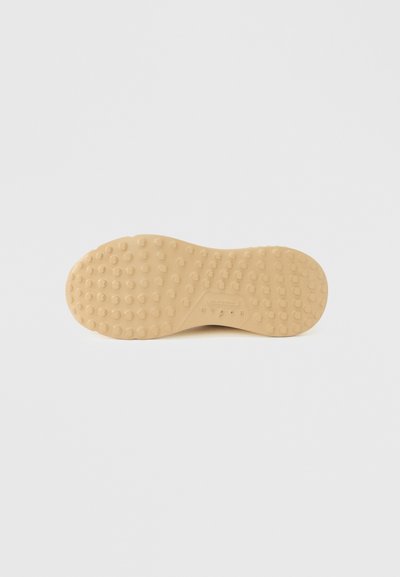 Καφέ καουτσούκ σόλα παπουτσιού με υφασμένη επιφάνεια που διαθέτει μικρές κυκλικές προεξοχές για καλύτερη πρόσφυση. Ομαλές άκρες και αποτύπωση λογότυπου κοντά στην πτέρνα.