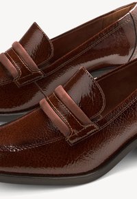Mocassini in pelle marrone con finitura lucida, dettagli in suede a contrasto e un design slip-on classico con cuciture decorative.