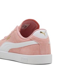 Baskets en daim rose avec semelle extérieure en caoutchouc blanc, dotées d'une bande latérale blanche et d'un logo doré sur le talon. Texture douce et design arrondi.