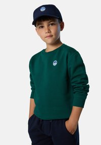 Grüner Pullover mit Rundkragen und gerippten Bündchen, mit einem kreisförmigen blauen Logo auf der Brust. Kombiniert mit einer dunkelblauen Kappe aus gewebtem Material.