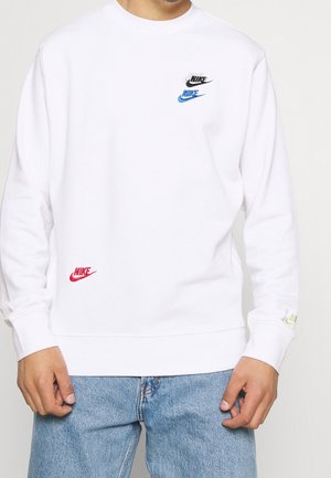 Witte Nike sweatshirt met kleurrijke logo's in zwart, blauw en rood op de borst, en een groene accenten op de mouw. Klassieke pasvorm en ontwerp.
