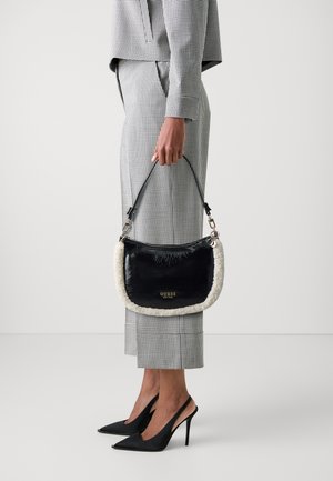 Borsa a tracolla nera in pelle sintetica con rifiniture in eco-pelliccia crema, caratterizzata da una forma curva, tracolla rimovibile e logo stampato in oro.