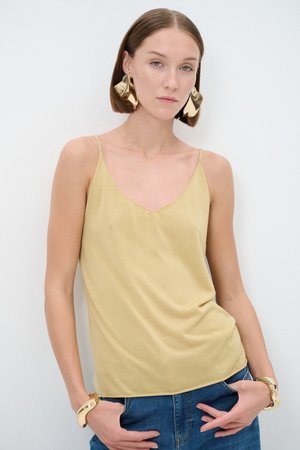 Helles gelbes Trägershirt mit dünnen Trägern, einem V-Ausschnitt und einer glatten Textur, kombiniert mit großen goldenen Statement-Ohrringen und einem Armband.
