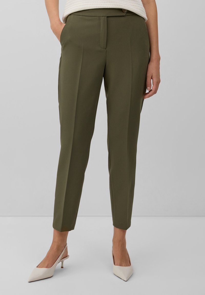 Pantalon vert olive ajusté avec une coupe slim, présentant un détail de couture avant, des poches latérales et une texture de tissu lisse.