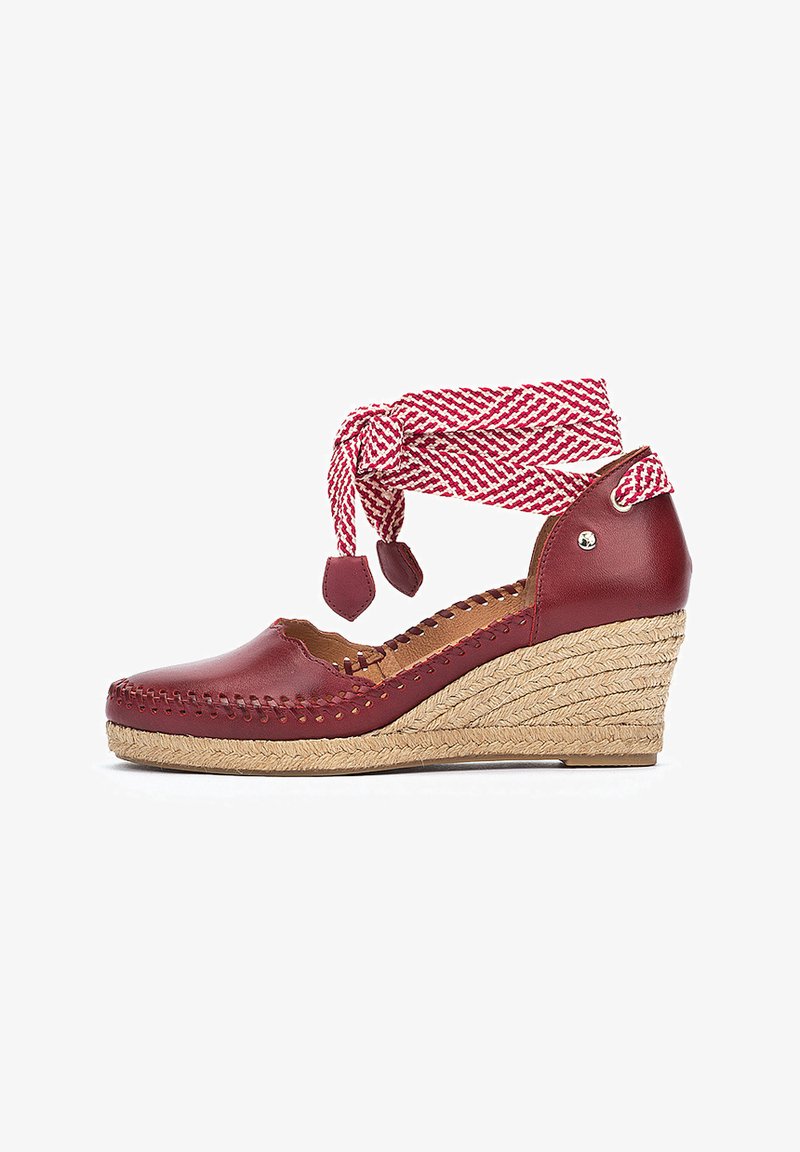 Escarpin compensé en cuir rouge avec un talon en jute tressé. Présente une sangle de cheville tissée rouge et blanche et des coutures décoratives le long des bords.