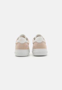 Sneakers in camoscio rosa e pelle bianca con una suola bianca testurizzata. Dettagli ondulati notevoli sul tallone e logo sulla suola.