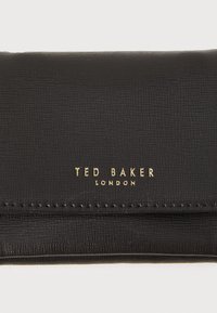 Carteira de couro preto texturizado com a marca "TED BAKER LONDON" em dourado na frente. Apresenta um design elegante e um estilo minimalista.
