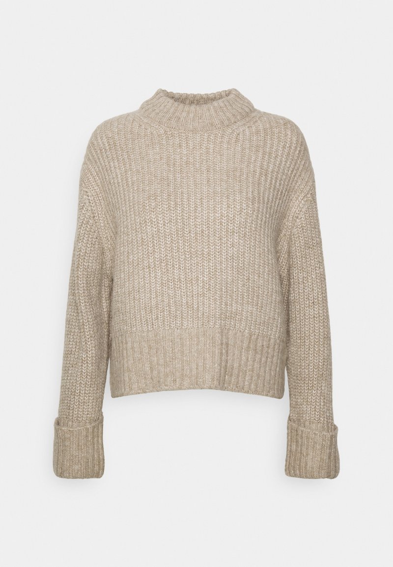 Pull beige en maille épaisse avec col montant côtelé, manches longues repliées aux poignets et un ourlet légèrement raccourci.