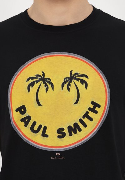 T-shirt en coton noir avec un graphique circulaire sur fond jaune, des palmiers noirs et le texte « PAUL SMITH » en police gras.