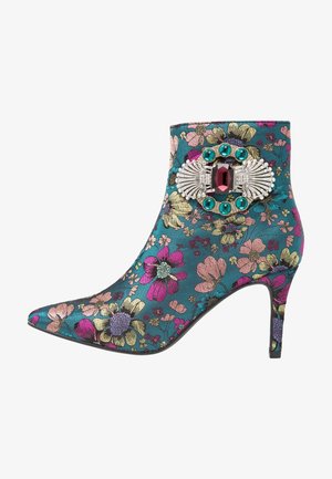 Botín de tobillo verde azulado con punta puntiaguda, patrón floral en rosa, amarillo, morado y un broche decorativo con joyas cerca del borde superior.