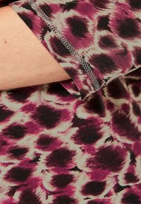 Tailliertes Oberteil in einem lebhaften lila, schwarz und cremefarbenen Tierdruck; aus weichem Stoff, mit rundem Halsausschnitt und zarter Naht entlang des Saums.