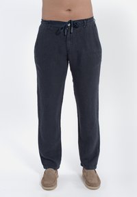 Donkerblauwe linnen broek met een elastische tailleband met trekkoord, taps toelopend ontwerp en zichtbare stiksels aan de naden.