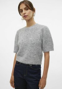 Grauer Wollmischpullover mit kurzen, leicht puffigen Ärmeln, rundem Halsausschnitt, strukturiertem Stoff und cropped Passform. Kombiniert mit dunklen Denim-Jeans.