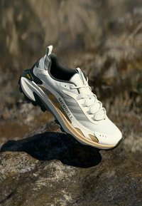 Letvægts Merrell sneaker i hvid og creme, med en tekstureret overdel, polstret sål med sorte og guld accenter samt robuste snørebånd.