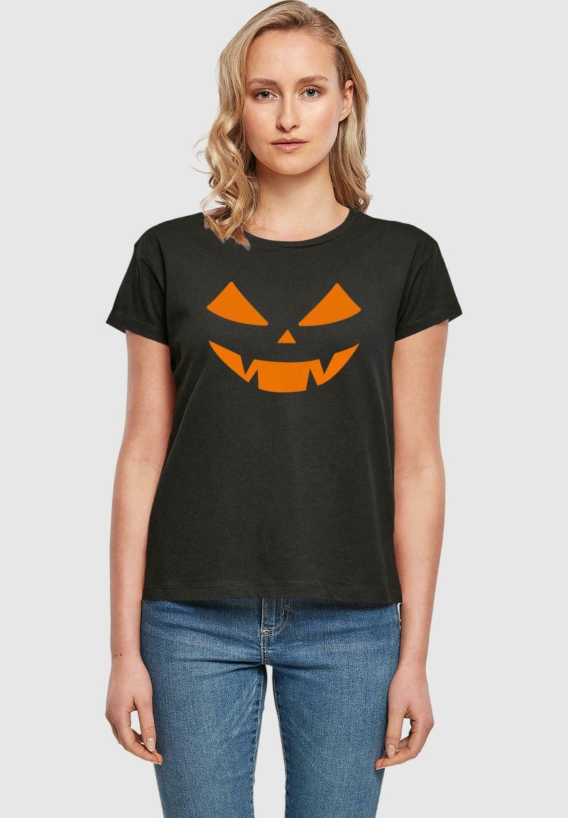 Mustapaita, jossa on lyhyet hihat ja etupuolella oranssi jack-o'-lantern -kasvokuva, jossa on kolmio-silmiä ja teräviä hampaita.