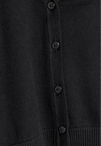 Tissu en tricot noir avec quatre boutons ronds noirs alignés verticalement sur un pied de col côtelé.