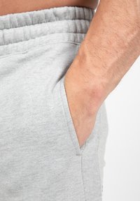 Lichtgrijze sweatpants met een trekkoord in de taille en zijzakken, gemaakt van zacht materiaal, met een gladde textuur en een eenvoudig ontwerp.