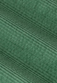 Close-up of green corduroy fabric showing its soft texture and distinctive vertical ridged pattern.