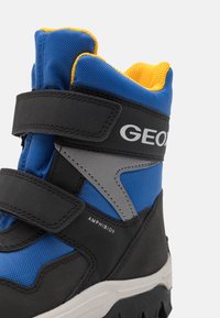 Botte montante bleue et noire avec doublure jaune, bretelles Velcro, semelle robuste et marquage "Amphibiox" ainsi qu'une partie du marquage "Geox".