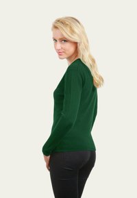 Pull vert à manches longues avec un design ajusté, fabriqué à partir d'un matériau doux, présentant un col rond et une texture côtelée aux poignets.