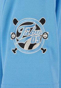 Šviesiai mėlynas tinklinis audinys su apvaliu išsiuvinėtu logotipu, kuriame yra "Tulus 05", šikšnosparnių ir beisbolo kamuoliukų juodai baltuose akcentuose.