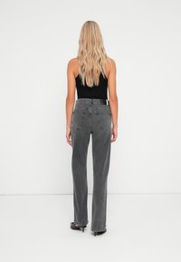 Jean en denim gris taille haute avec une coupe droite, doté de deux poches arrière, d'un dégradé subtil et d'une finition texturée.