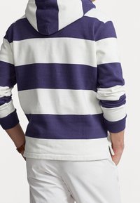 Hoodie a rayas moradas y blancas con capucha, con puños y dobladillo acanalados. Fabricado en material suave, diseñado para comodidad y uso casual.