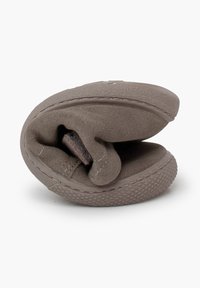 Zapatilla gris plegada con una suave textura de ante, forma redondeada y suela de goma texturizada. Cuenta con detalles de costura y un diseño minimalista.