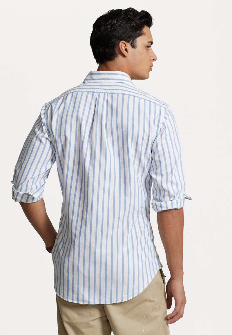Camicia a maniche lunghe da uomo a strisce bianche e azzurro chiaro, con polsini abbottonati, dettaglio della piega sul retro e orlo curvo, realizzata in un tessuto leggero.